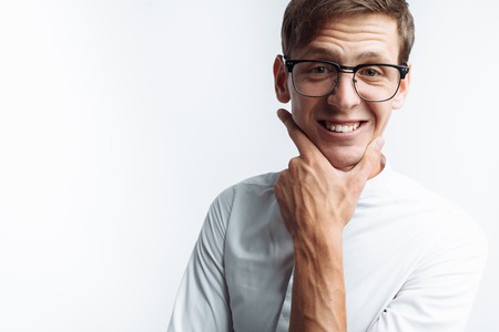 Portrait of young attractive guy in glasses depicting joy, in white shirt isolated on white background,の写真素材