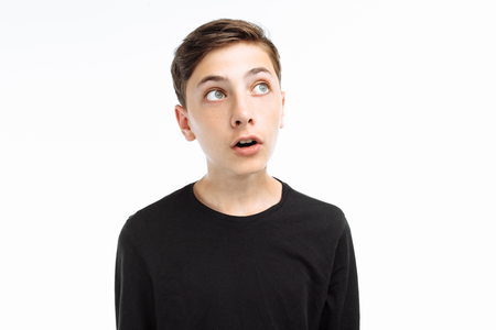 Photo emotional teenager, guy in black t-shirt, shows the emotion of surprise, on a white background,の写真素材