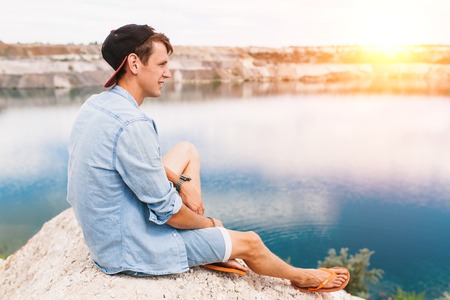 Portrait of a man sitting on a rock, travel around the island, a tourist on vacation, handsome guyの写真素材