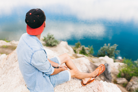 Portrait of a man sitting on a rock, travel around the island, a tourist on vacation, handsome guyの写真素材