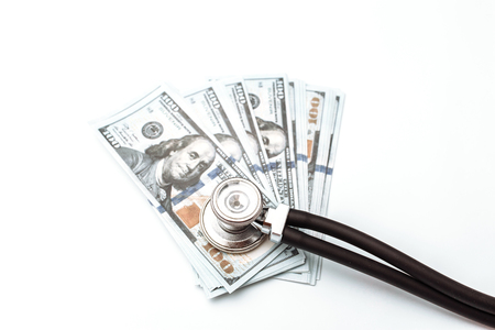 Lots of bills of 100, dollars and stethoscope, American banknote, green background with cash currency close-upの写真素材