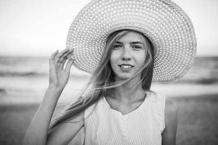 Beautiful portrait of a girl in a hat close-up, rest on the sea or ocean, a woman in a summer blue dressの写真素材