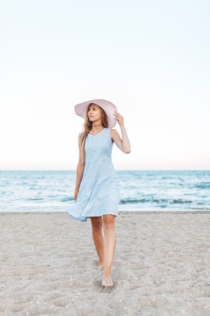 Beautiful portrait of a girl in a hat close-up, rest on the sea or ocean, a woman in a summer blue dressの写真素材