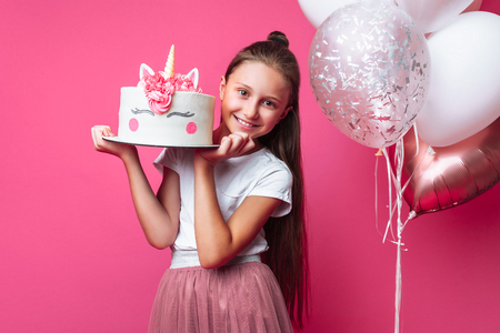 girl with a cake for a birthday, in the Studio on a pink backgroundの写真素材