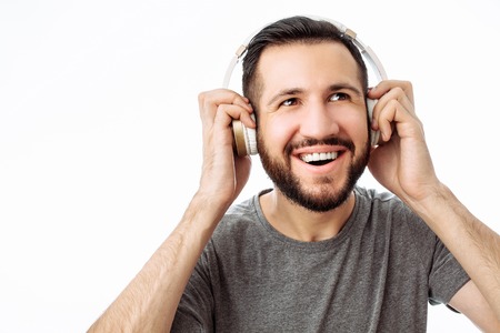 Happy hipster man, in gray t-shirt, smiling, listening to music in headphones. on white background.