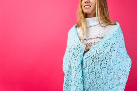 The girl threw a warm shawl on her shoulders, on a red background, handmade scarves.の写真素材