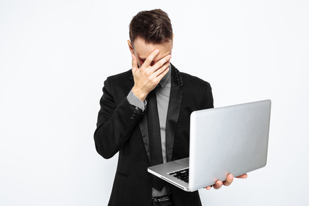 Successful man, in black suit, looking sadly at laptop, Bank clerk, white background, black Friday, discounts, shoppingの写真素材