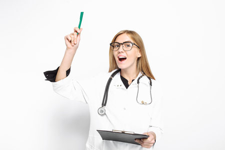A woman doctor, with a stethoscope around her neck, is standing with a medical history, and the idea came to her, she remembered what she had forgotten, on a white background. medicine conceptの写真素材