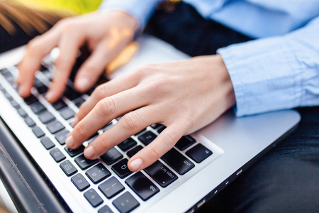 Girl working on a laptop, hands typing text, closeup in the park. Business conceptの写真素材