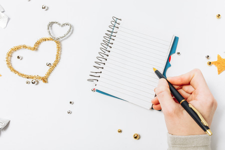 Top view of women writing a goal to make a list for the new year or Christmas on a notebook, Christmas decoration. On a white backgroundの写真素材