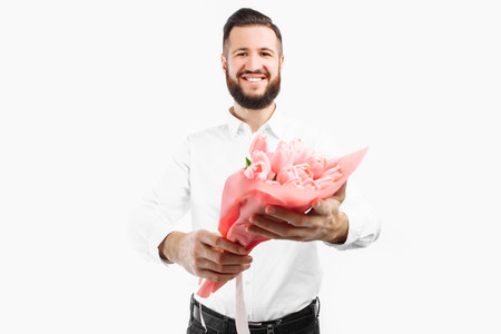 Elegant man with a beard holding a bouquet of tulips, a gift for Valentine's Day. On a white backgroundの写真素材