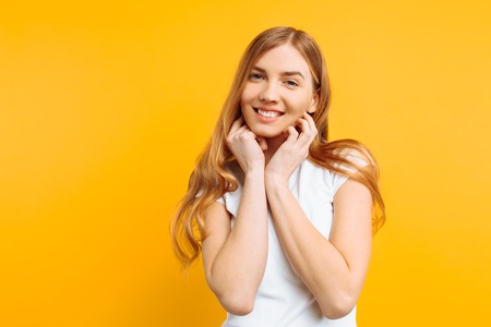beautiful girl in white t-shirt holding hands near face, portrait of cute womanの写真素材