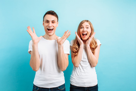 Photo of an emotional pair of a man and a woman in white T-shirts screaming with surprise or delight...