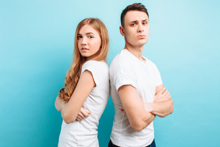 Happy loving couple, man and woman, dressed in white T-shirts, back-to-back and smiling, against a...