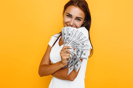 Photo of an attractive young woman standing smiling, with banknotes, winning money in an online...