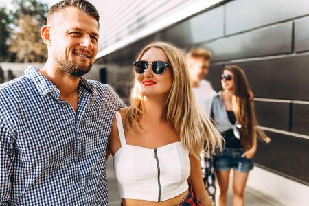 A group of young friends, girls and guys walking together in the fresh air in the city, talking and...