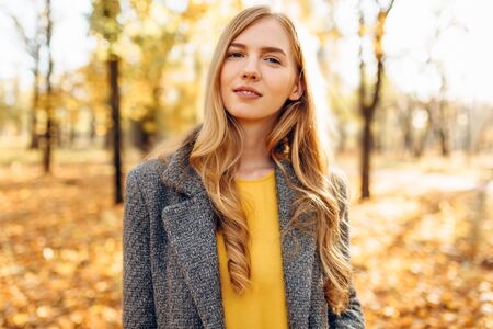 Beautiful stylish young girl walking outdoors in autumn. Young woman enjoying autumn weather.の写真素材