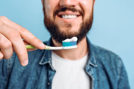 A young man with a toothbrush on a blue background, the concept of care for the oral cavity, the oral hygieneの写真素材