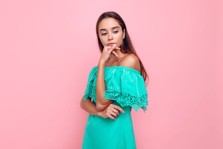 Attractive pensive sexy girl in a dress, dreamily looking at a copy of the space on a pink backgroundの写真素材