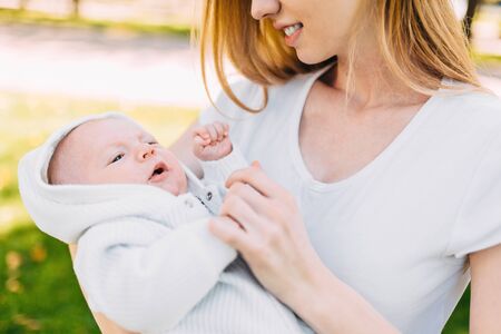 Mother and newborn baby. A mother holds her young son in her arms while walking in the Park in Sunny weather. Mother's dayの写真素材