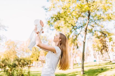 Mother and newborn baby. A mother holds her young son in her arms while walking in the Park in Sunny weather. Mother's dayの写真素材