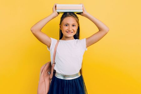 A book roof over your head. A teenage girl holds a book on a yellow background. Development and education.の写真素材