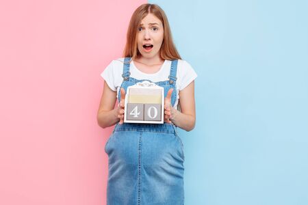 The 40 weeks of pregnancy. A stunned young beautiful pregnant woman poses holding a sign with the...