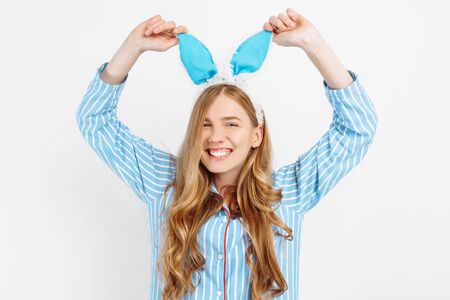 Portrait of a cute beautiful girl in pajamas, with Bunny ears on her head, a beautiful and cheerful woman in pajamas, on a white backgroundの写真素材