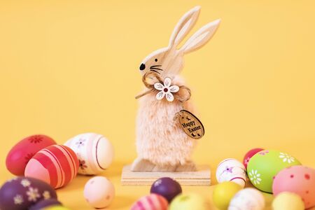 Wooden Easter Bunny with Easter eggs, on an isolated yellow background. Concept of Easter...