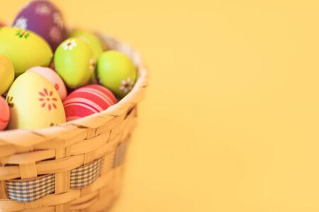 Colorful Easter eggs in a basket on an isolated yellow background. Concept of Easter decorations, Easterの写真素材