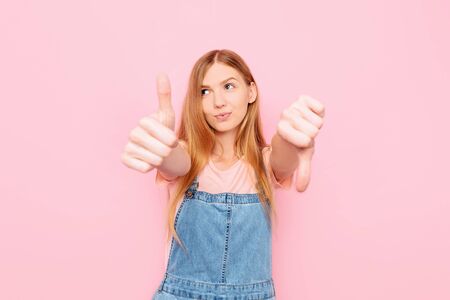 A young attractive stylish woman makes a good-bad sign. Undecided between Yes or no, on an isolated...