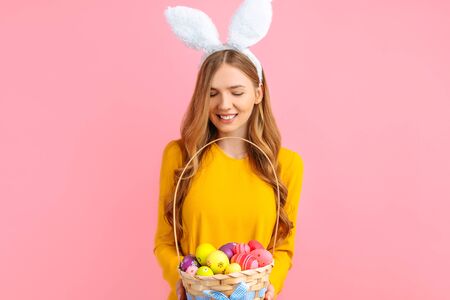 Happy Easter. A beautiful happy young woman wears rabbit ears on Easter day and holds a basket of...