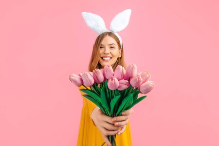happy Easter. Happy attractive woman in Easter Bunny ears, girl with a bouquet of tulips, on an...