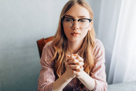 Young thoughtful businesswoman sitting at the tableの写真素材