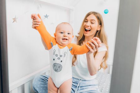 Happy family, Mother and child on a white bed. Mom and baby boy are playing. A parent and a small...