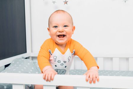 A small child in pajamas lies on the bed and crawls, preparing for sleep