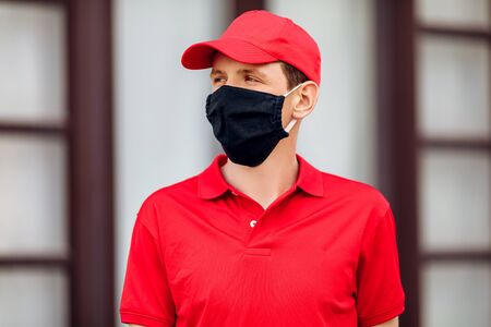 A courier in uniform and wearing a medical protective mask. Fast delivery by transport. Online stores and Express delivery. Quarantine, coronavirusの写真素材