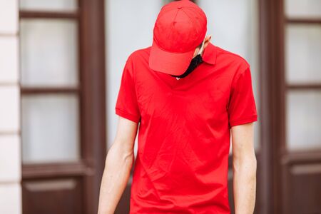 A courier in uniform and wearing a medical protective mask. Fast delivery by transport. Online...