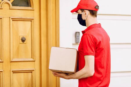 A courier in a protective medical mask with boxes in his hands delivers parcels. Service delivery in terms of quarantine, pandemic coronavirusの写真素材