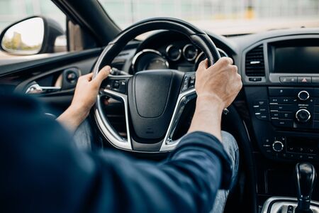 Close-up of a man's hand holding the steering wheel while driving a carの写真素材
