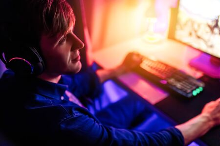 professional gamer playing computer games online with headphones, in a room with neon light.の写真素材