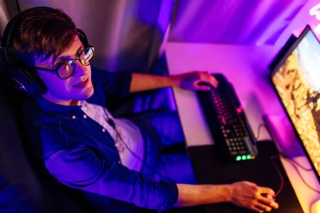 A professional gamer plays online video games in the first person on his personal computer, sitting...