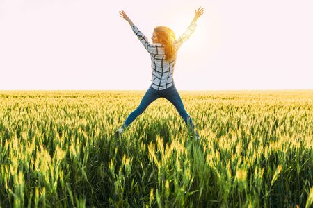 Happy excited woman jumps up in Golden wheat, in a wheat fieldの写真素材