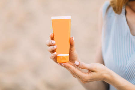 Woman's hands with sunscreen, against the background of the sea. Summer vacation