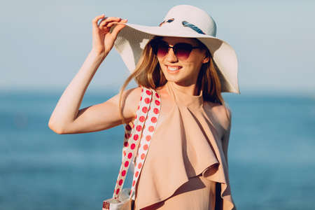An attractive girl in a summer hat and swimsuit, walking on the beach . Summer vacation, seaの写真素材