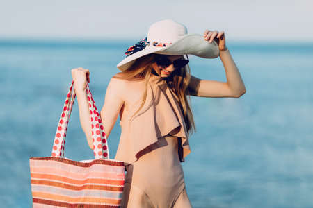 attractive girl in a summer hat and swimsuit, walking on the beach . Summer vacation, seaの写真素材