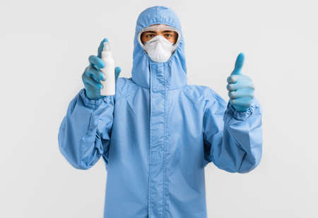 male doctor in a protective suit against coronavirus, wearing gloves, glasses and a medical mask,...