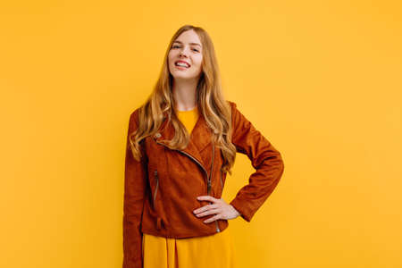 attractive happy beautiful girl, in a bright yellow dress and autumn jacket, poses on an isolated...