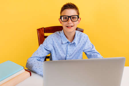 distance education for children. a student is sitting at a table, studying by video link with a...