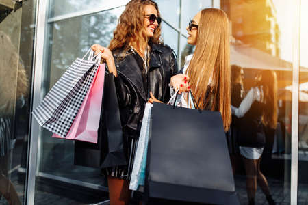 Happy shopping friends. Two beautiful young women with shopping bags, on the background of a...